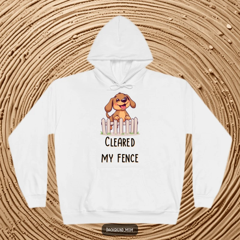 Funny Kawaii Dachshund Hoodie depicting a dog with a joyful expression mid-leap over a miniature fence.