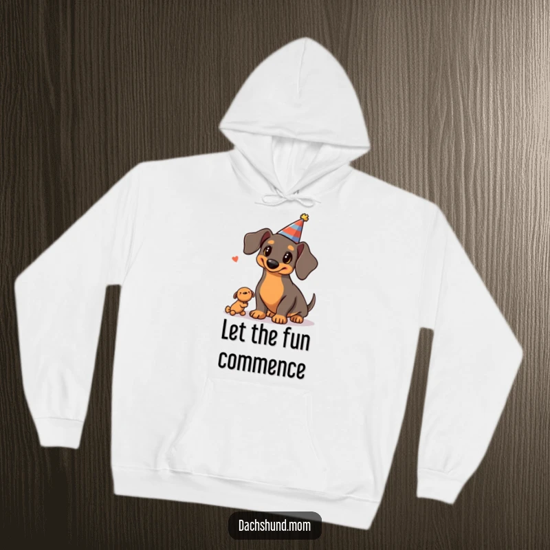 Funny Kawaii Dachshund Hoodie: a cute dachshund in a party hat is juggling three squeaky toys with impressive skill, looking festive.