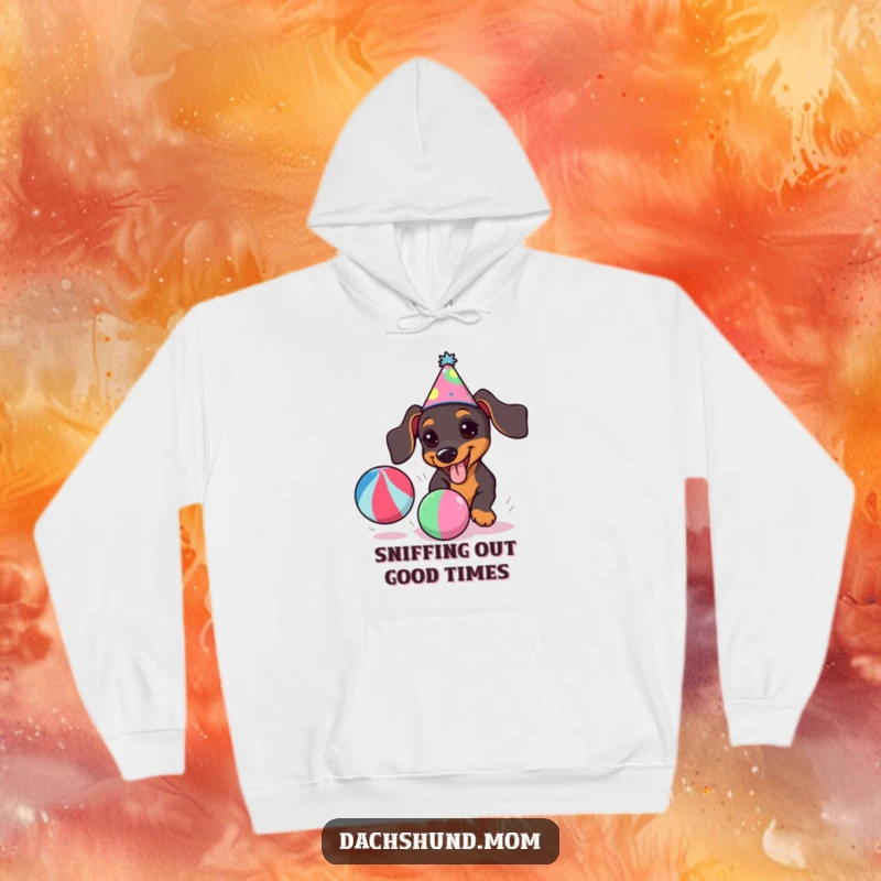 Funny kawaii dachshund wearing a party hat, joyfully chasing a colorful ball, featured on a cozy hoodie.