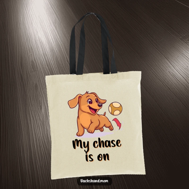 Funny tote bag with a happy, small wiener dog enthusiastically chasing a bouncing ball, ready for any outing.